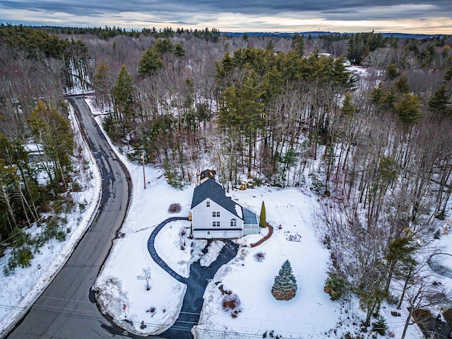 snowy aerial view featuring a forest view