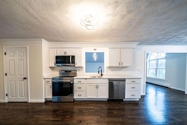 kitchen with light countertops, baseboard heating, appliances with stainless steel finishes, white cabinets, and a sink