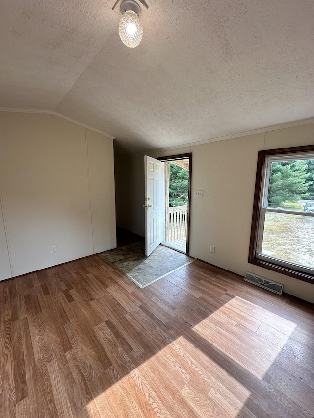 interior space featuring lofted ceiling, visible vents, a textured ceiling, and wood finished floors