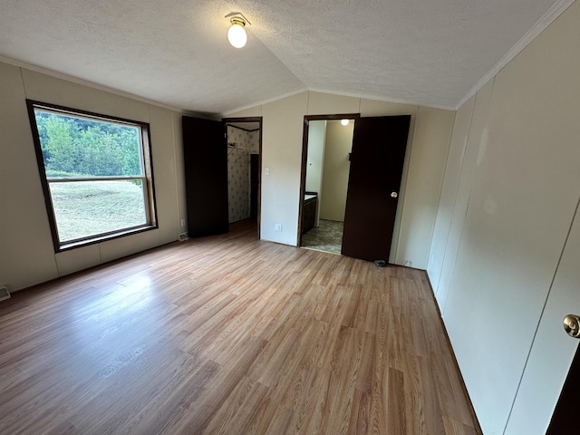 unfurnished bedroom with light wood-style flooring, ornamental molding, vaulted ceiling, and a textured ceiling