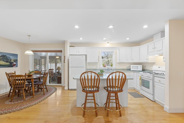 kitchen with white appliances, light wood-type flooring, a sink, and white cabinets