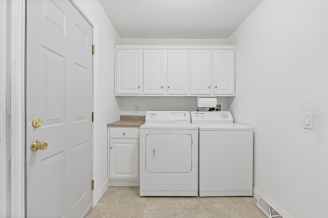 washroom featuring visible vents, washing machine and clothes dryer, cabinet space, and baseboards