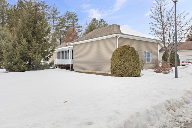 view of snowy exterior featuring a sunroom and a chimney