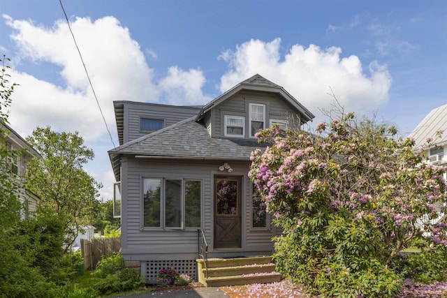 bungalow-style home with entry steps, a shingled roof, and fence