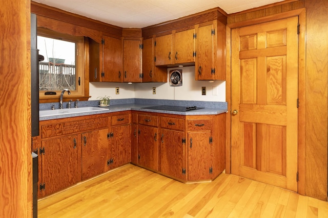 kitchen with light wood finished floors, visible vents, brown cabinets, and a sink