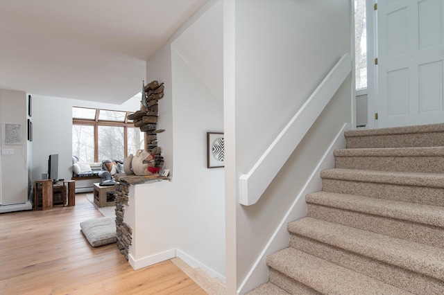 stairs with baseboards, baseboard heating, and wood finished floors