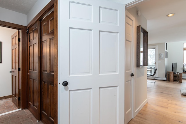 corridor featuring light wood finished floors, baseboards, and recessed lighting