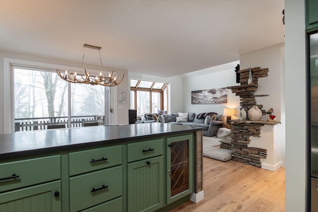 kitchen featuring dark countertops, wine cooler, light wood-type flooring, a chandelier, and green cabinetry