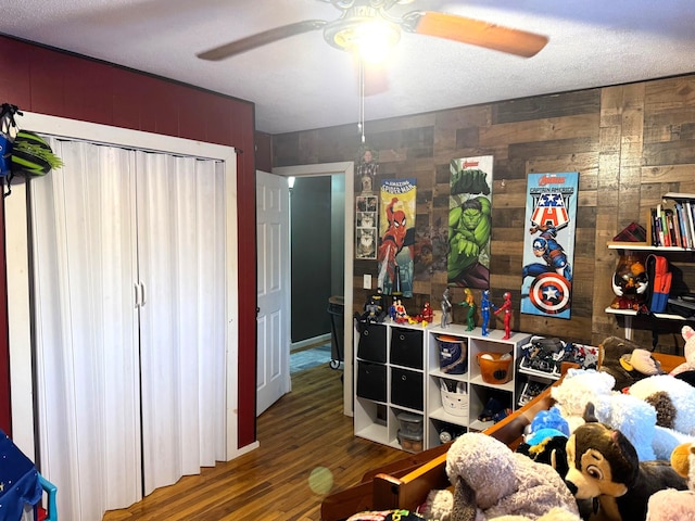 bedroom with wood walls, a ceiling fan, and wood finished floors