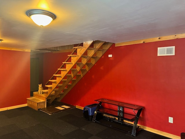 finished basement featuring visible vents, baseboards, and stairs