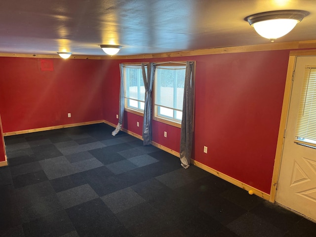 unfurnished room with dark floors and baseboards