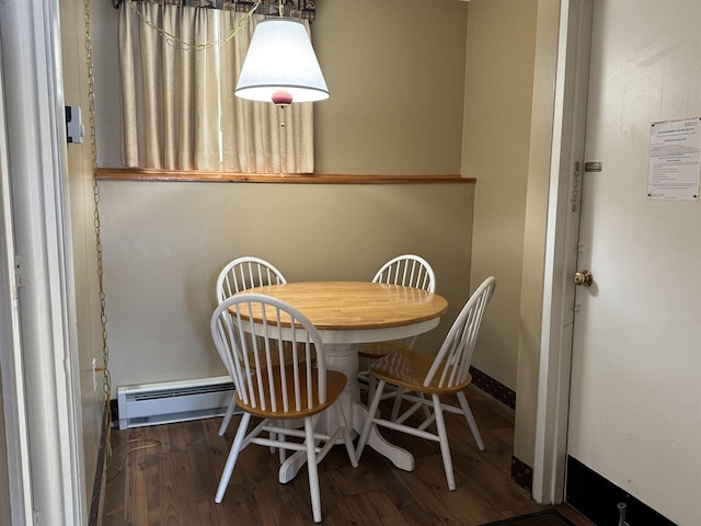 dining space featuring a baseboard heating unit, wood finished floors, and baseboards