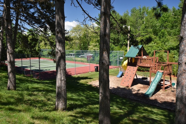 view of sport court featuring fence, playground community, and a yard