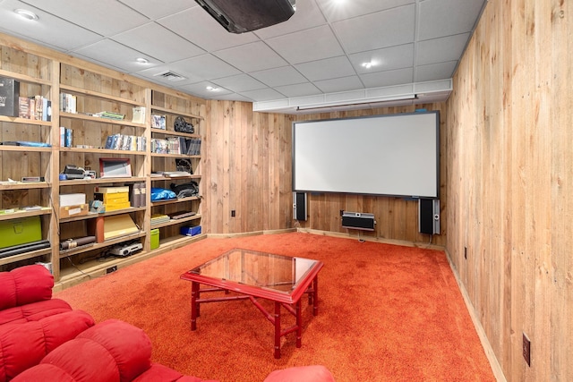 carpeted cinema room featuring wooden walls and visible vents