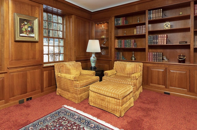 living area with carpet and wooden walls