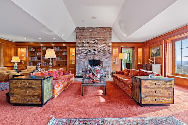 living room featuring wooden walls, lofted ceiling, carpet flooring, a brick fireplace, and built in shelves