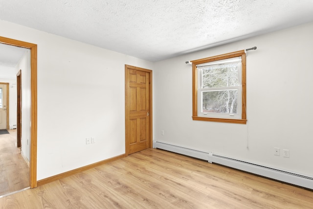 unfurnished room with a baseboard heating unit, light wood-style floors, a textured ceiling, and baseboards