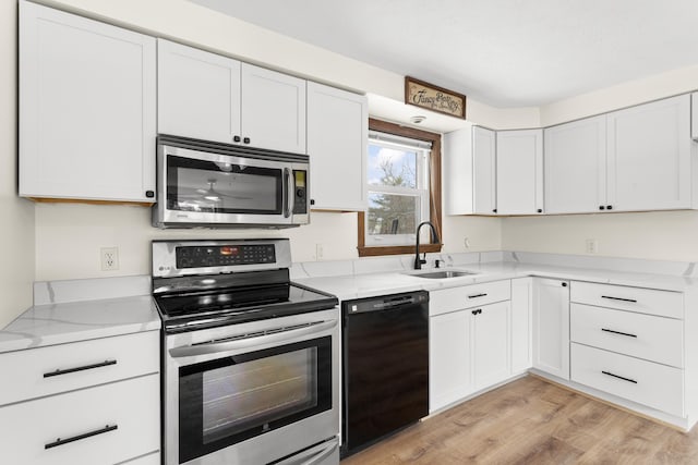 kitchen featuring light wood-type flooring, white cabinetry, stainless steel appliances, and a sink