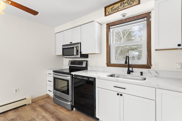 kitchen with light stone counters, a baseboard heating unit, a sink, white cabinetry, and appliances with stainless steel finishes