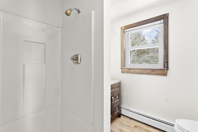 bathroom with a shower, vanity, baseboard heating, and wood finished floors