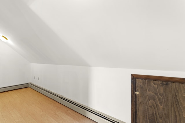 bonus room with a baseboard radiator, vaulted ceiling, and light wood finished floors