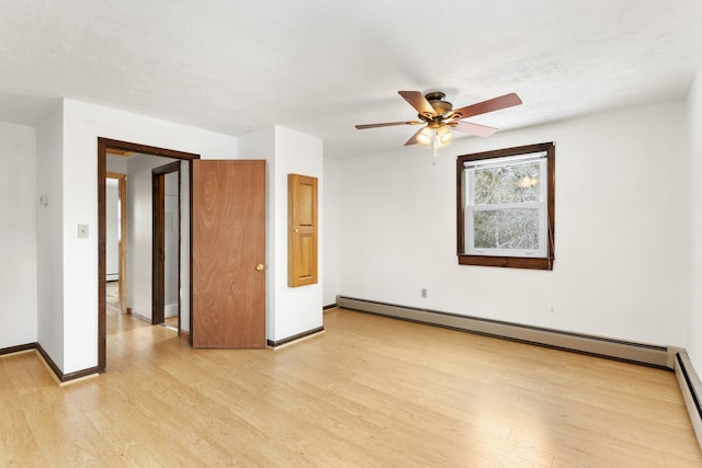 unfurnished bedroom with a baseboard heating unit, light wood-style flooring, baseboards, and a ceiling fan