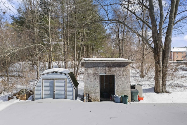 snow covered garage with a storage unit