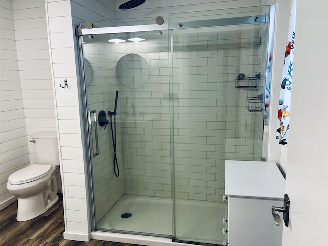 full bath with a shower stall, toilet, and wood finished floors