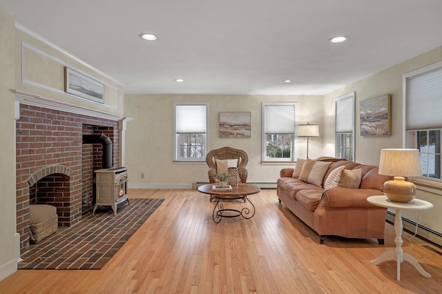 living room with a wood stove, wood-type flooring, a baseboard radiator, and recessed lighting