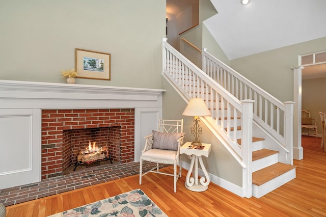 interior space featuring lofted ceiling, a brick fireplace, baseboards, and wood finished floors