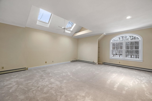 carpeted spare room featuring vaulted ceiling with skylight, baseboard heating, and crown molding