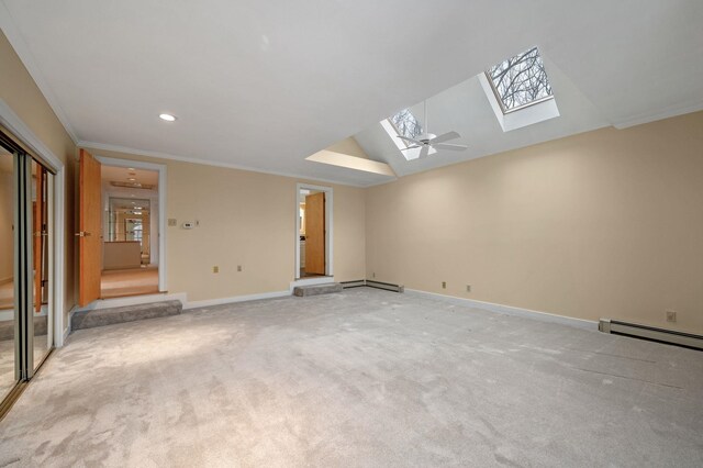 empty room featuring light carpet, vaulted ceiling with skylight, and baseboards