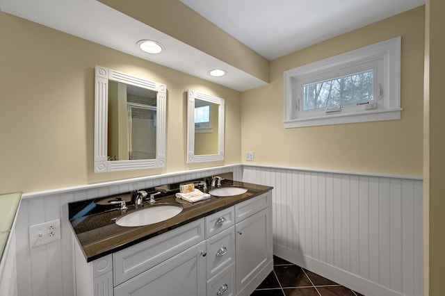 full bathroom with double vanity, a wainscoted wall, a sink, and tile patterned floors