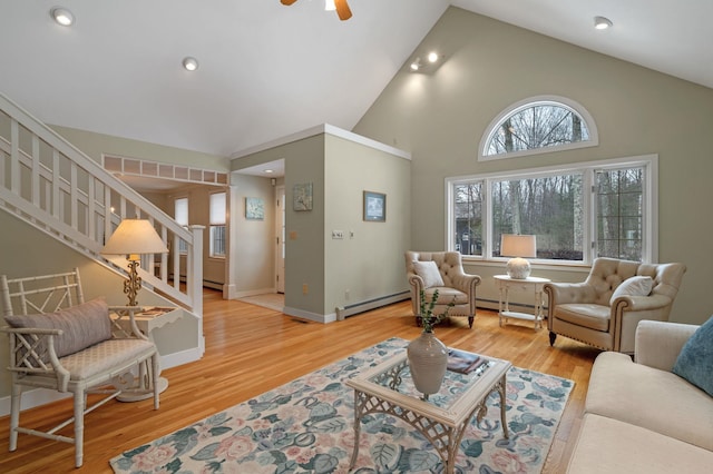 living area featuring light wood-style floors, a baseboard heating unit, and stairway