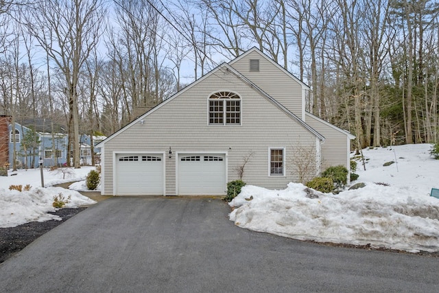 view of snow covered exterior with a garage and driveway