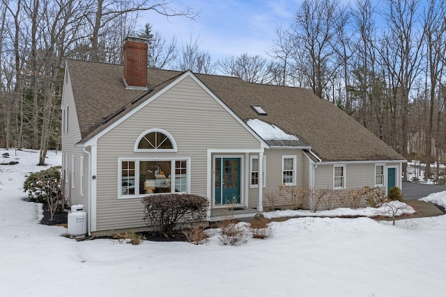 view of front of house with a shingled roof and a chimney