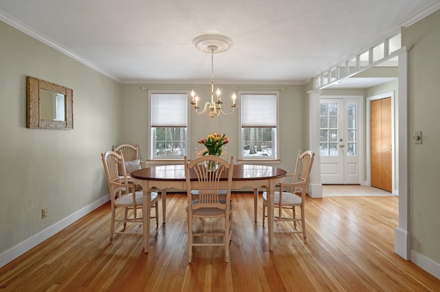 dining space with light wood-style floors, ornamental molding, baseboards, and an inviting chandelier