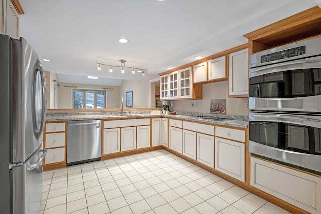 kitchen featuring light tile patterned floors, stainless steel appliances, a sink, light countertops, and glass insert cabinets