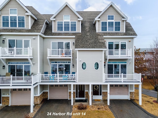 view of front of home with aphalt driveway, stone siding, a garage, and roof with shingles