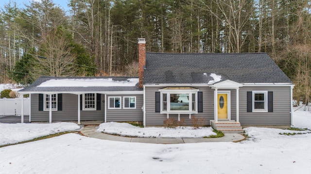 view of front of property with roof with shingles, a chimney, and fence