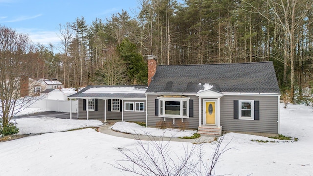 view of front of house featuring roof with shingles, a chimney, and fence