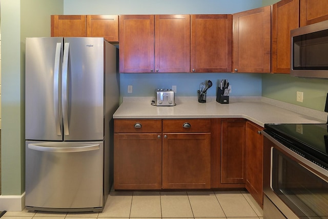 kitchen featuring stainless steel appliances, light tile patterned flooring, and light countertops