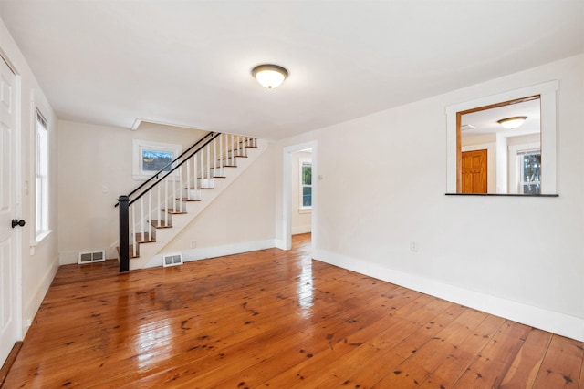 interior space with hardwood / wood-style flooring, baseboards, stairs, and visible vents