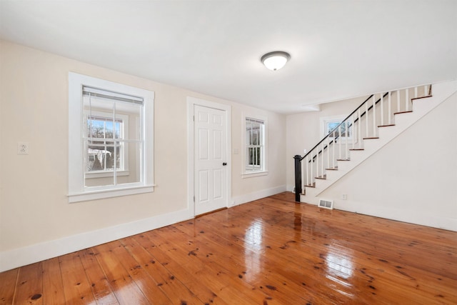 foyer featuring hardwood / wood-style flooring, baseboards, stairs, and visible vents