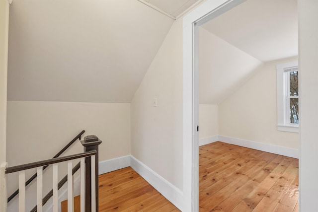 additional living space with vaulted ceiling, light wood-style flooring, and baseboards