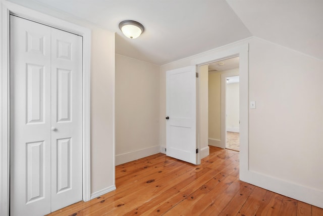 interior space featuring lofted ceiling, a closet, baseboards, and light wood finished floors