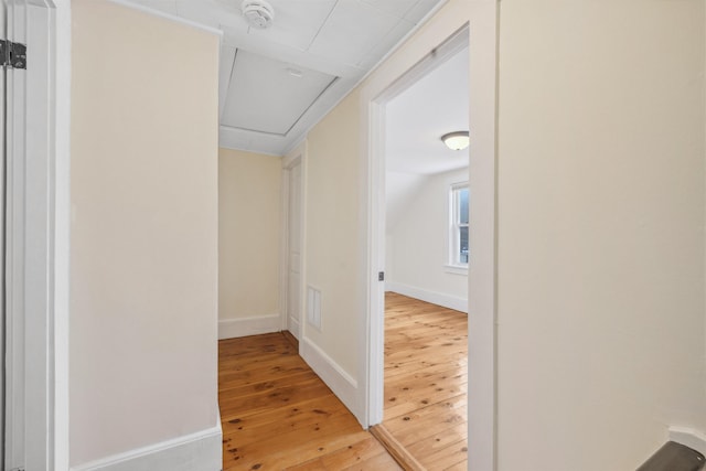 hall with lofted ceiling, baseboards, light wood-style flooring, and attic access