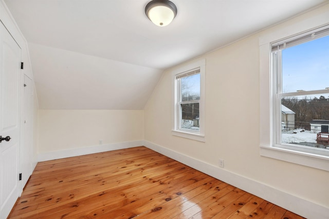 additional living space with lofted ceiling, light wood finished floors, and baseboards