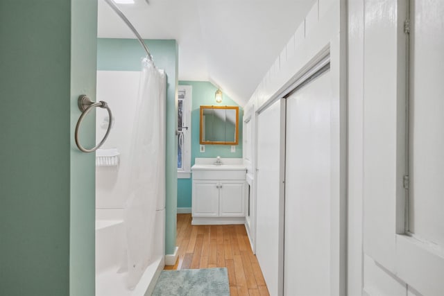 full bath featuring lofted ceiling, curtained shower, wood-type flooring, and vanity