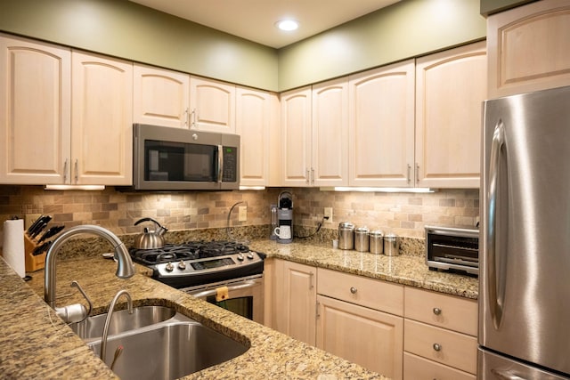 kitchen with decorative backsplash, appliances with stainless steel finishes, light stone counters, a sink, and recessed lighting